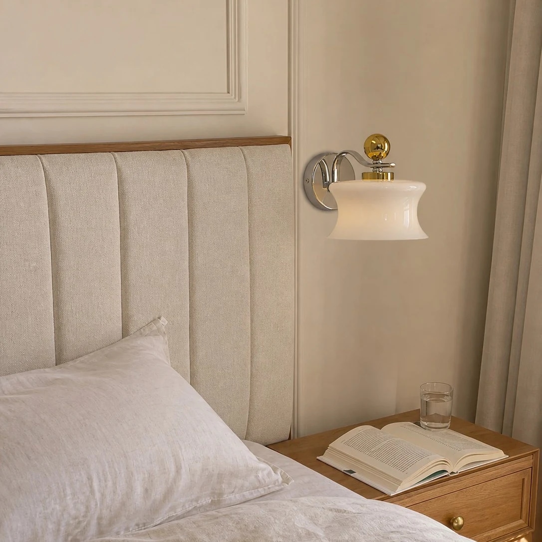 Applique murale en verre crème installée à côté du lit