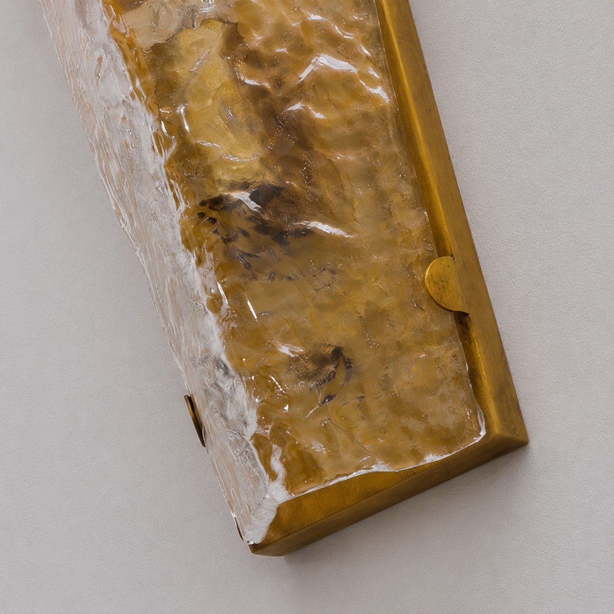 Detalle cercano del vidrio texturizado transparente y el marco de cobre.