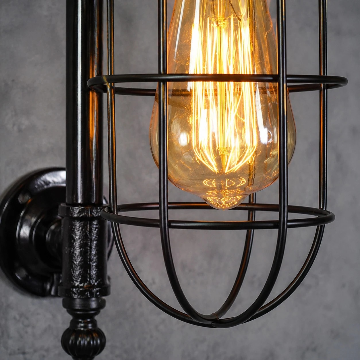 Industriële wandlamp met buisconstructie en vintage kooivormige lampenkap.