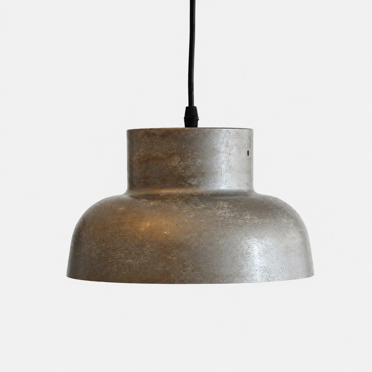 Lámpara colgante industrial de metal envejecido sobre fondo liso.