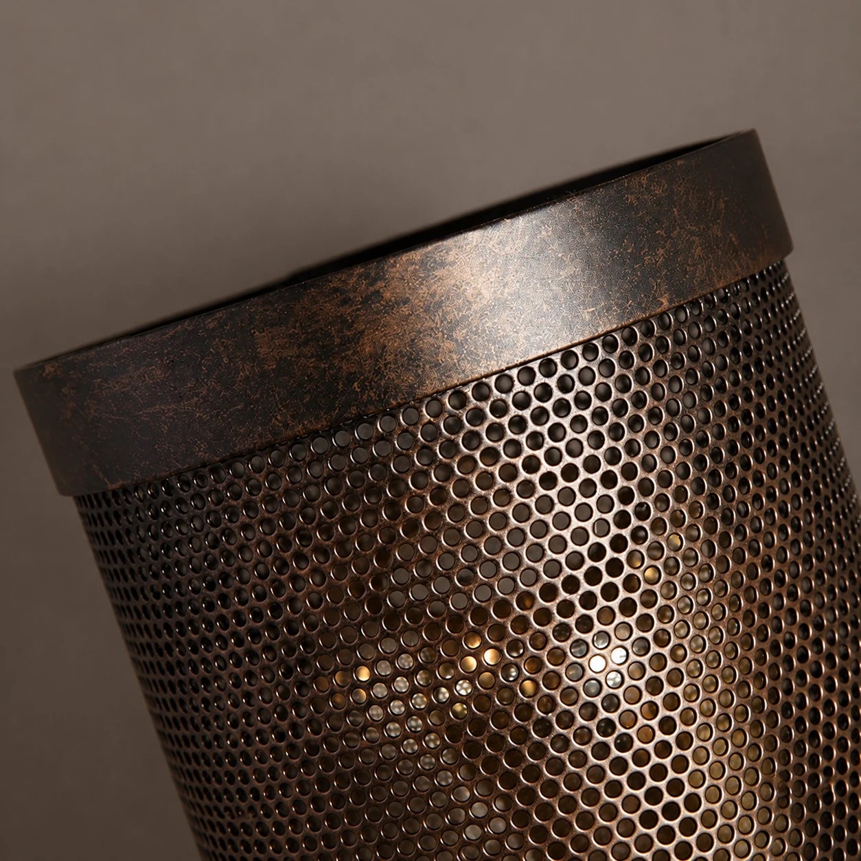 La lueur chaude de l'ampoule est visible à travers l'abat-jour en métal perforé.