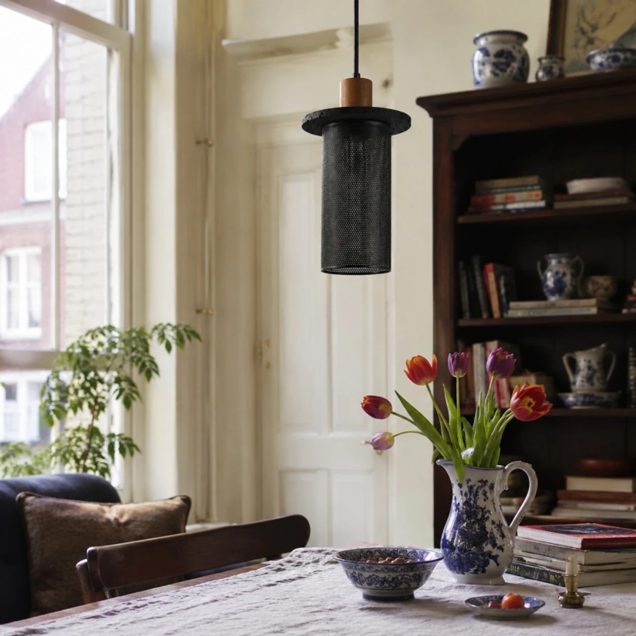 Svart vävd näthängande lampa ovanför ett matbord vid fönstret