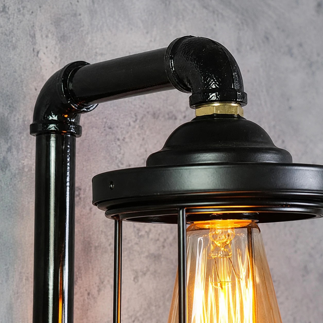 Detailopname van een industriële buiswandlamp met vintage kooivormige lampenkap.