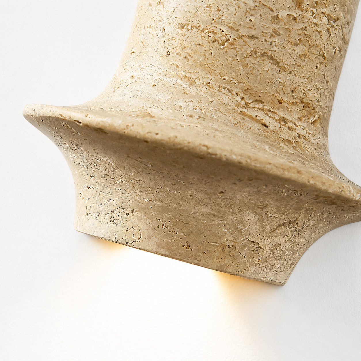 Lit travertine wall sconce detail showing warm downward glow