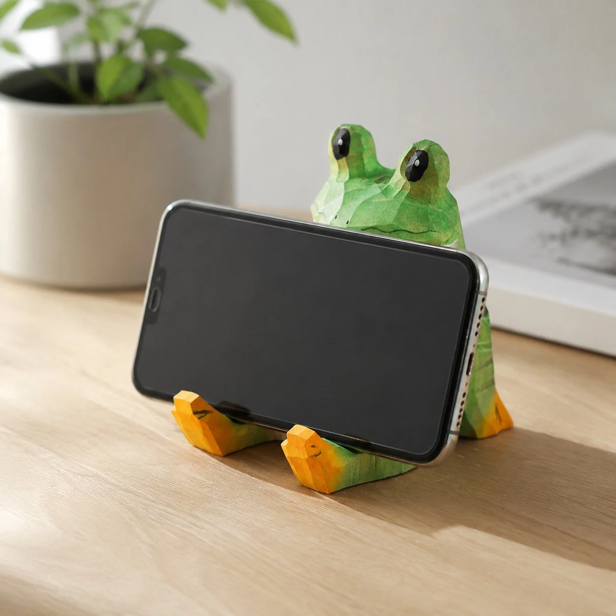 Frog wooden phone stand holding a phone