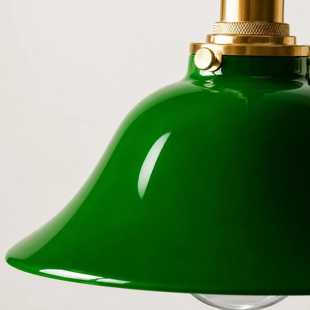 Lampada a sospensione in vetro verde con attacco in ottone e paralume curvo.