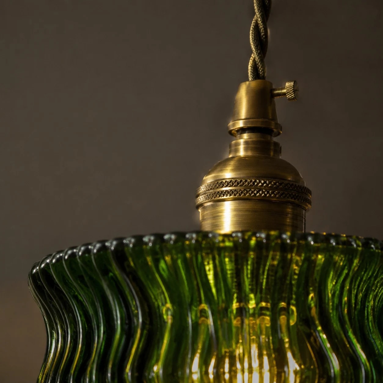Dettaglio della testa della lampada color ottone sopra il paralume in vetro verde