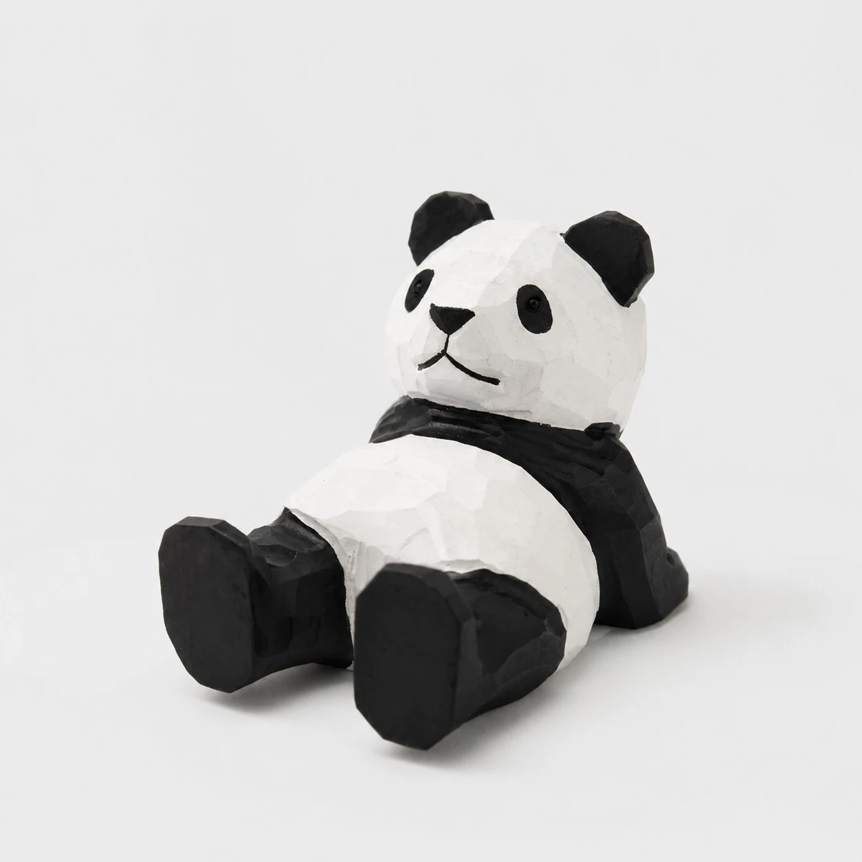 Telefoonstandaard in de vorm van een liggende panda, handgesneden uit hout.