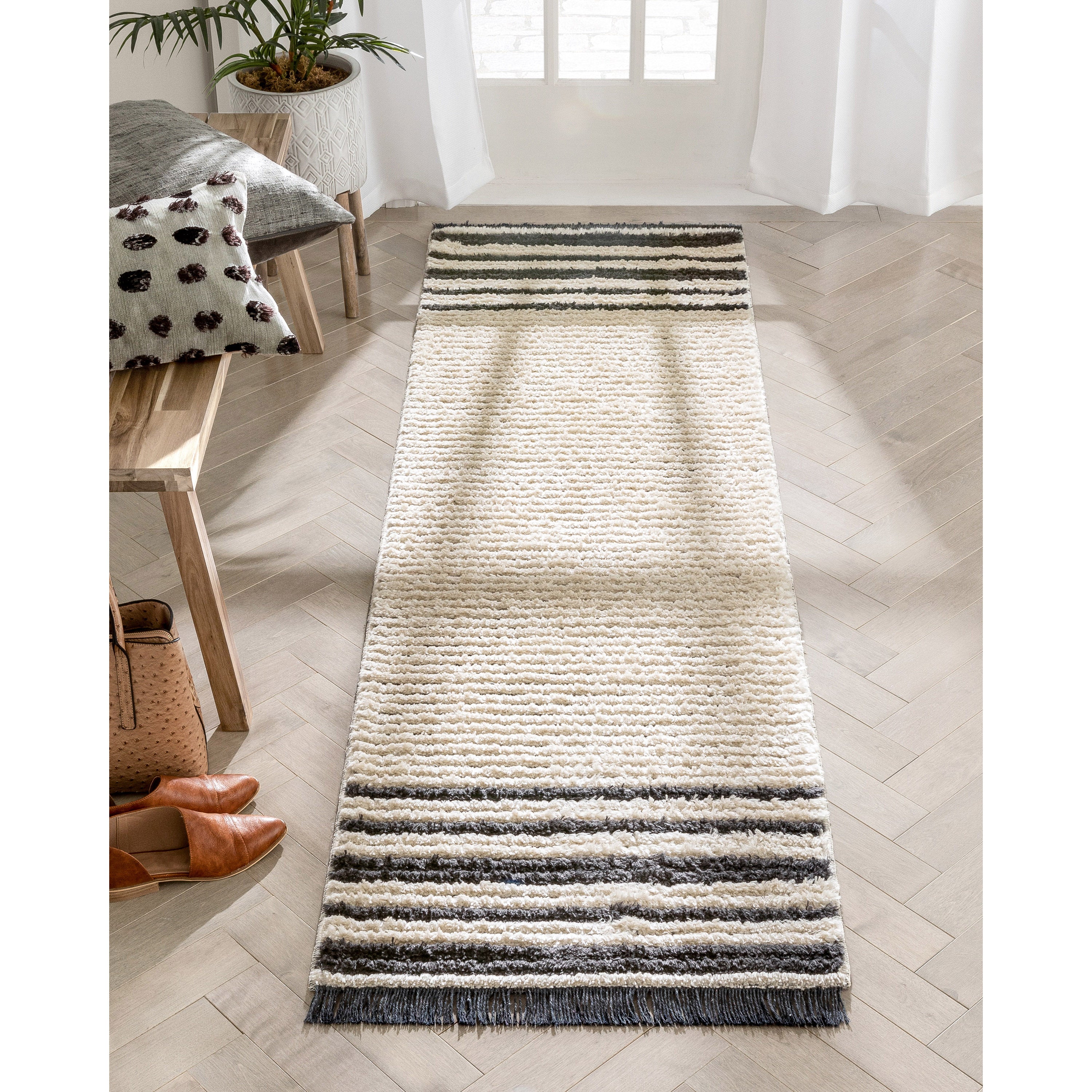 Adriel Tribal-Teppich mit festem Randmuster und elfenbeinfarbenem High-Low-Strukturflor