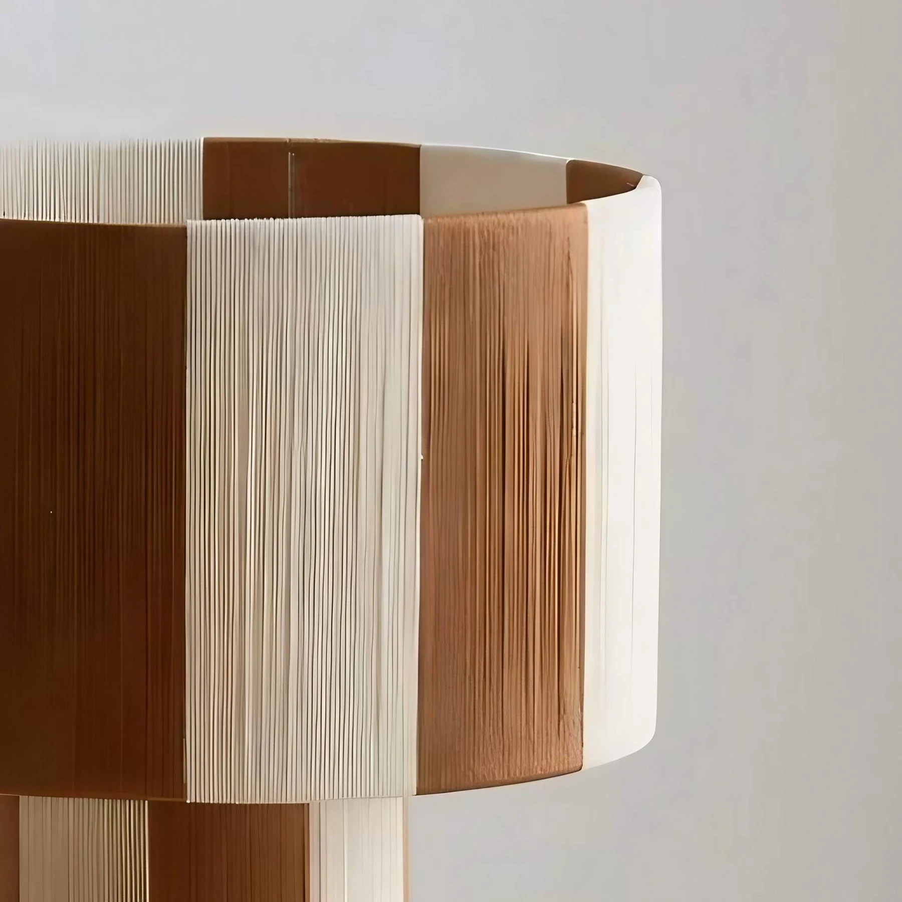 Detalhe aproximado dos painéis do abajur trançados em tons de café e creme.