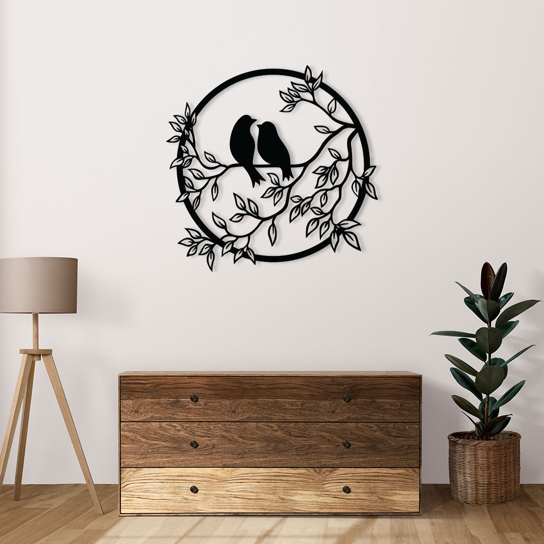 Circular black metal wall art with two birds and leafy branches