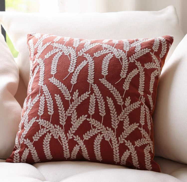 Red pillow cover with cream raised leaf-like pattern on a sofa
