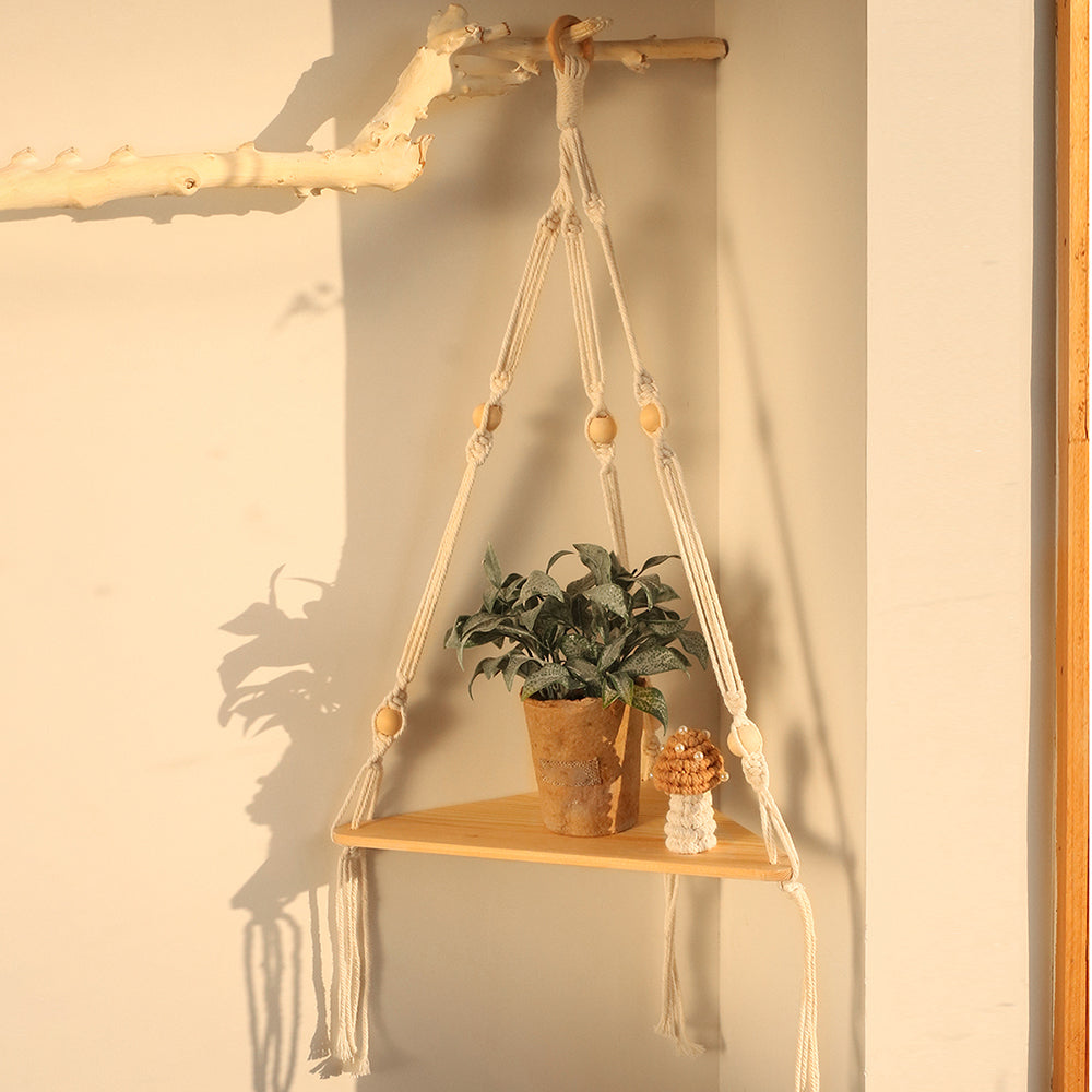 Single wooden corner shelf suspended by cream macrame cords