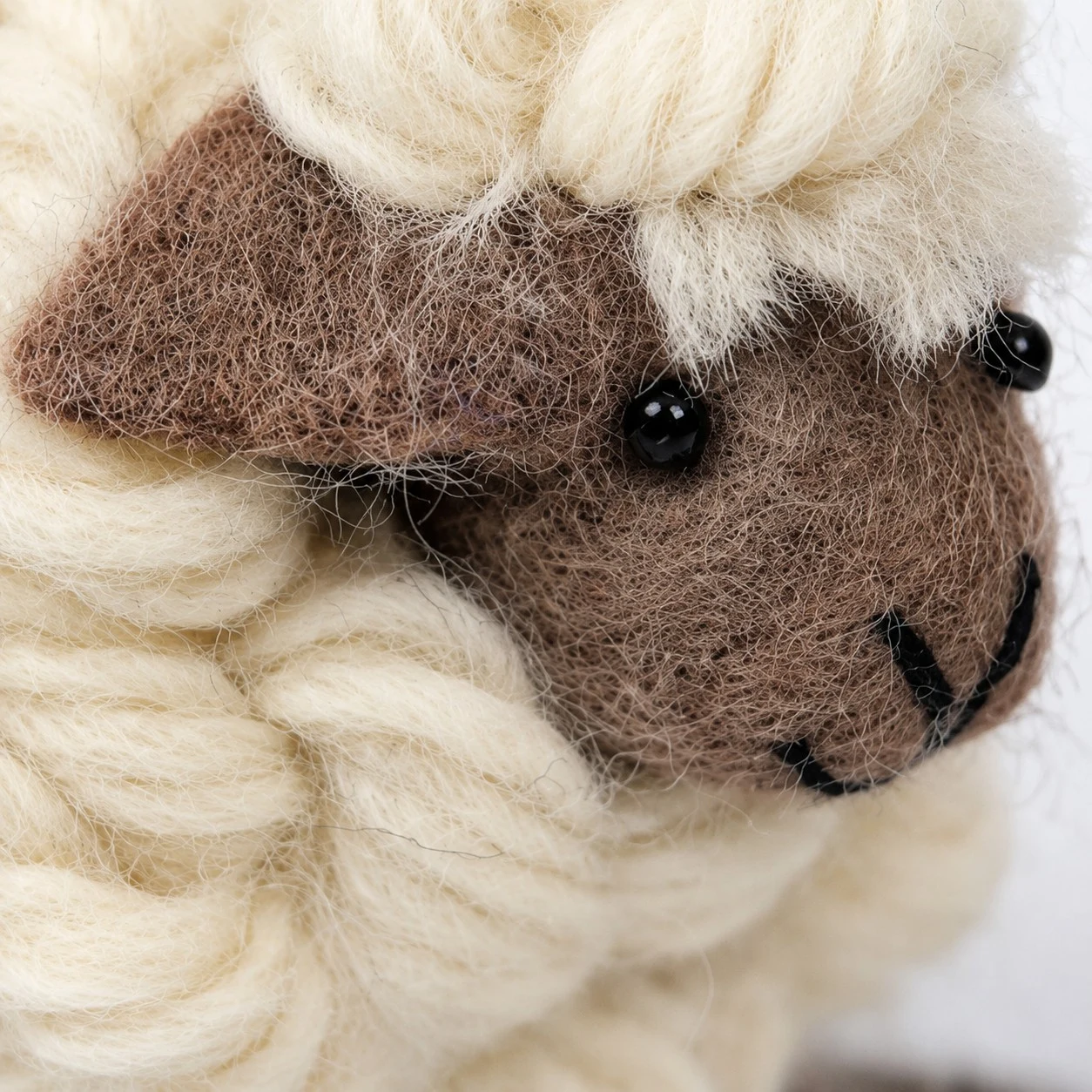 vue de dos d'un mouton en laine fait main avec une toison bouclée couleur crème