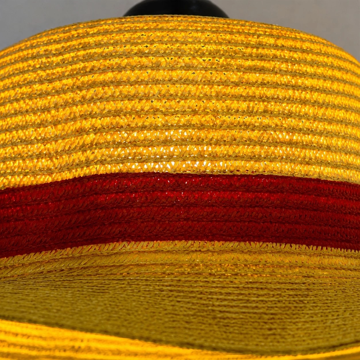 Textura de palha em camadas, aba larga e uma elegante faixa vermelha como destaque.