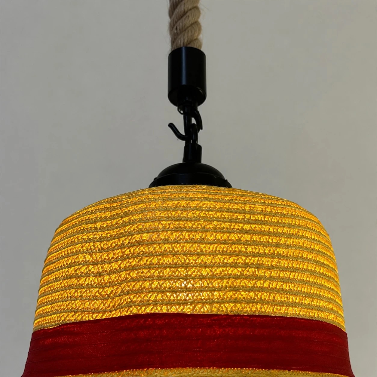 Textura de palha em camadas, aba larga e uma elegante faixa vermelha como destaque.