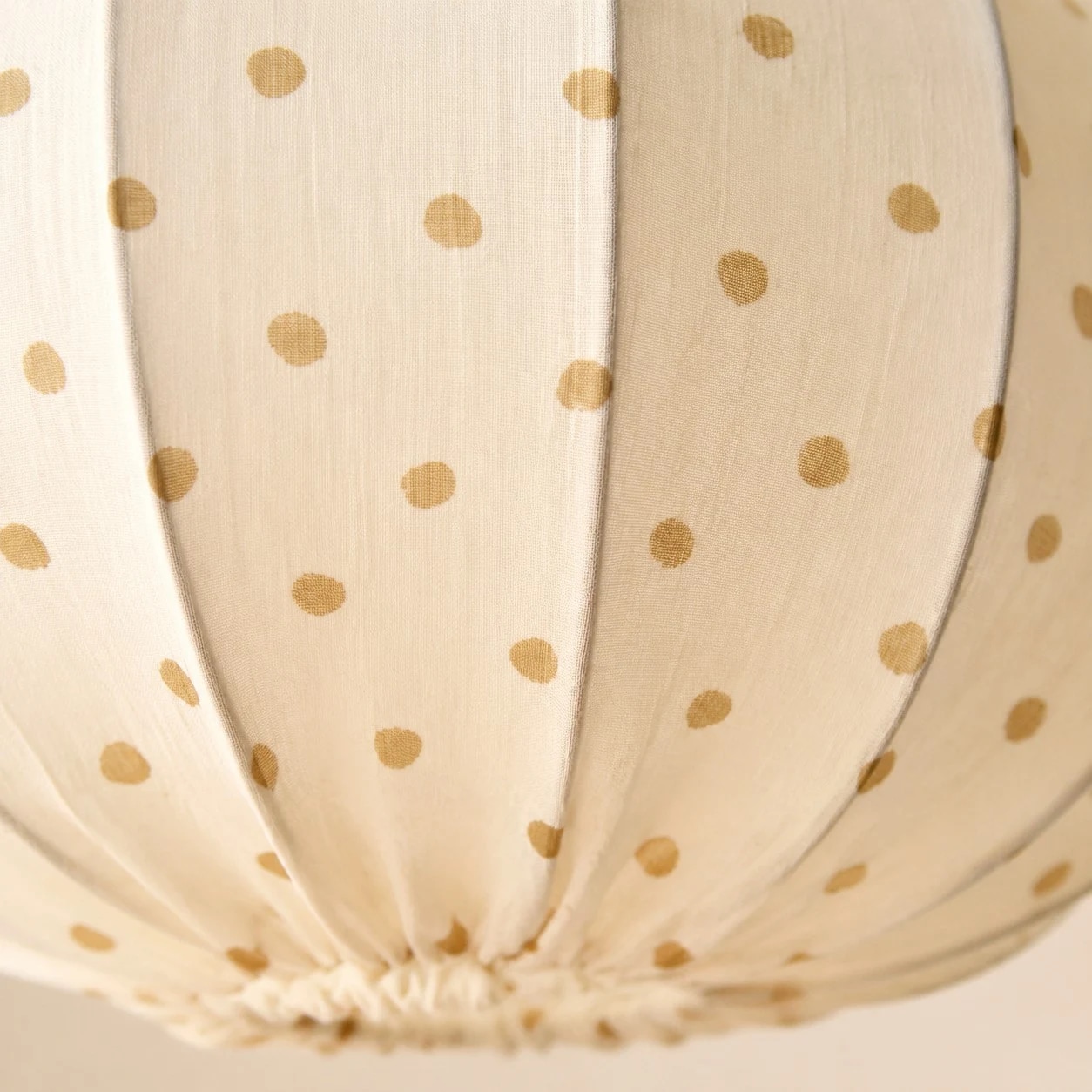 Gathered fabric folds, warm dotted print and a softly rounded shade.