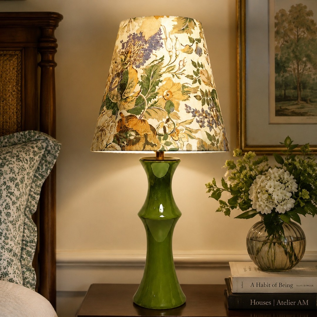 Beige floral fabric table lamp glowing on a bedroom side table