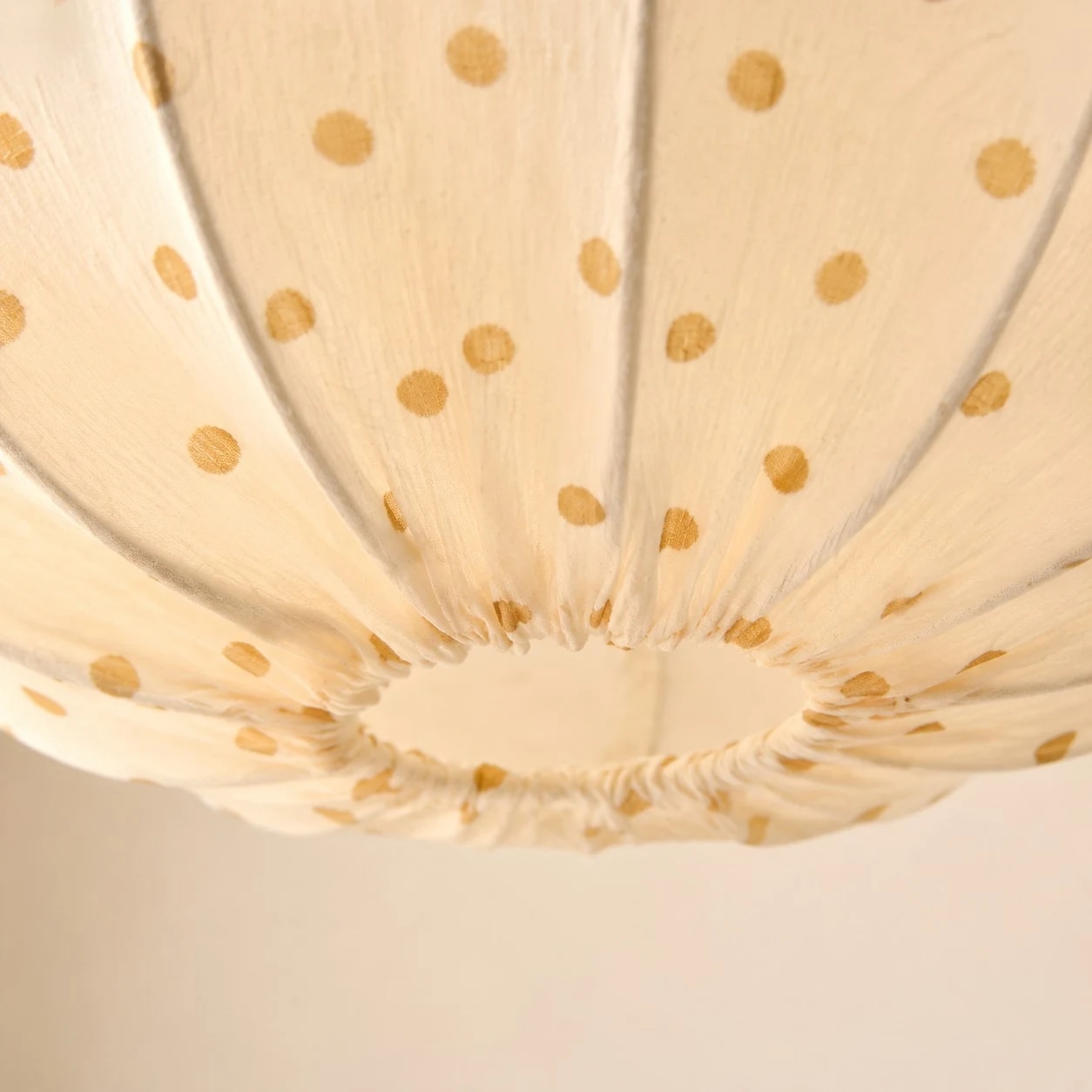 Gathered fabric folds, warm dotted print and a softly rounded shade.
