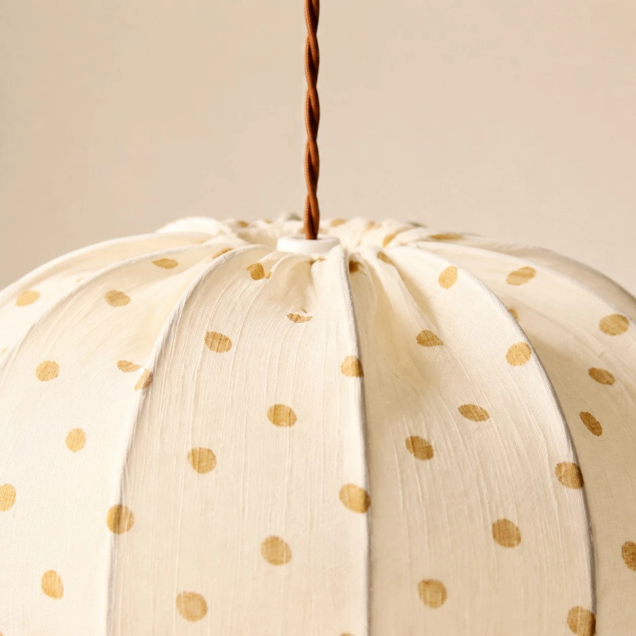 Gathered fabric folds, warm dotted print and a softly rounded shade.