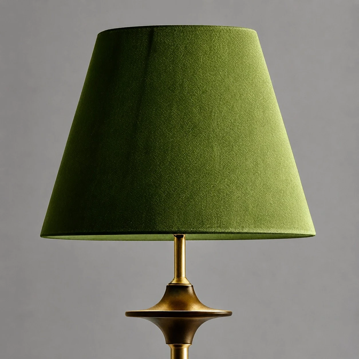 Abajur com cúpula de tecido verde e haste em tom de latão.