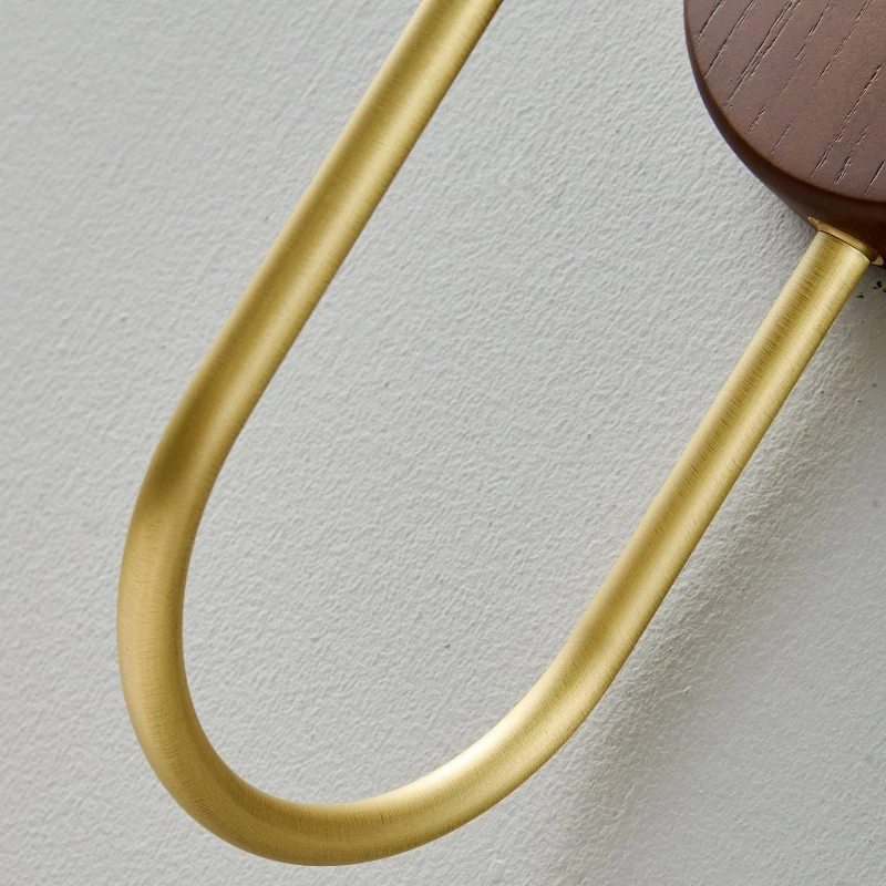 The rounded wood backplate gives the fixture a soft furniture-like presence, while the curved metal arm keeps the shade lifted and balanced.