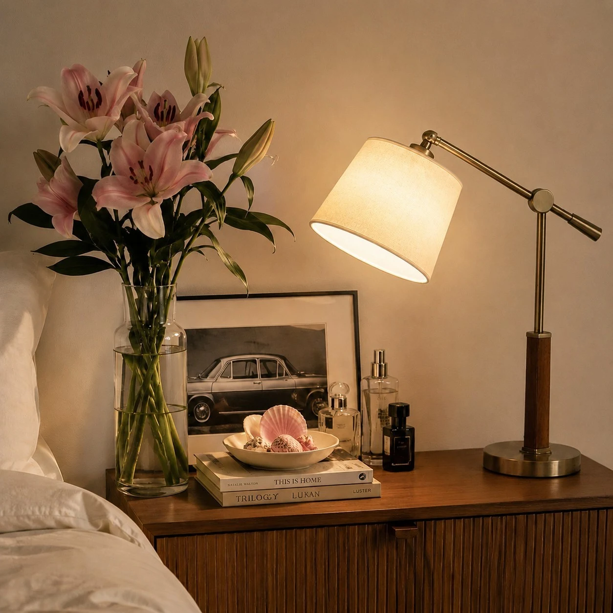white fabric swing arm table lamp lit beside books and flowers