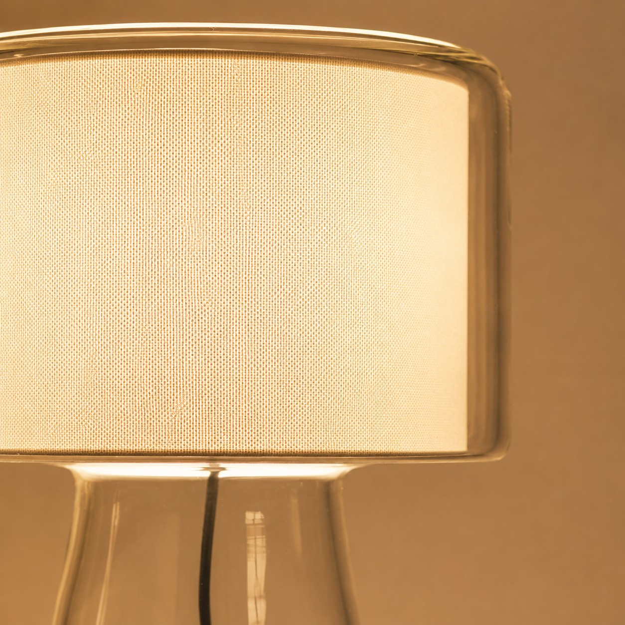 Lampada da tavolo in vetro naturale con paralume in tessuto.