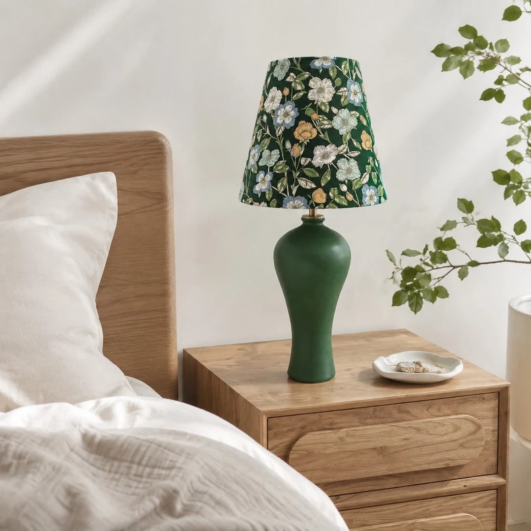 Green floral ceramic table lamp on a bedside table