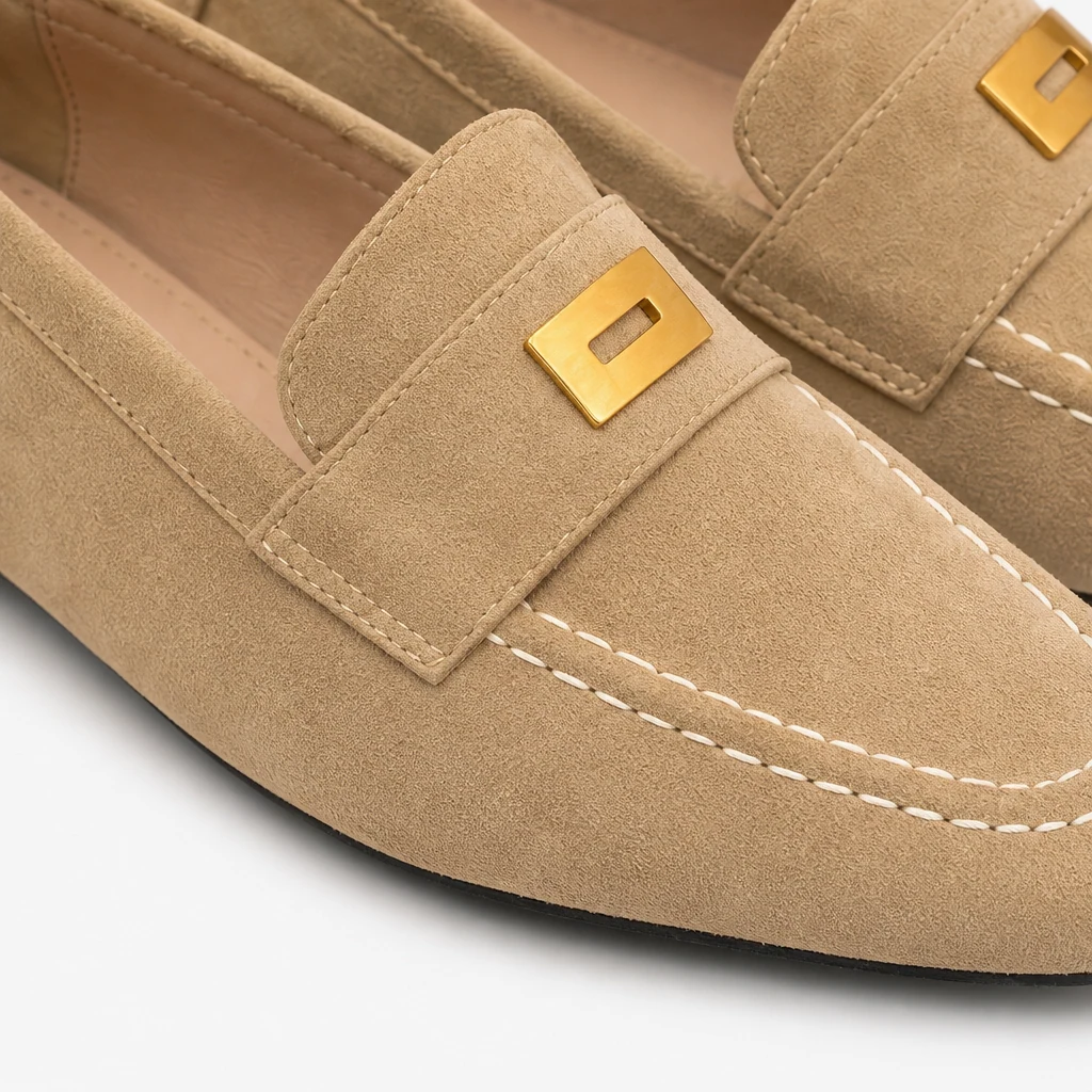 Close-up of suede-look penny loafer texture, stitching, and metal accent